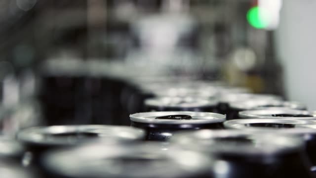 Automatic Canning Machine Transports Aluminum Cans with a Conveyor Belt in an Indoor Manufacturing Facility