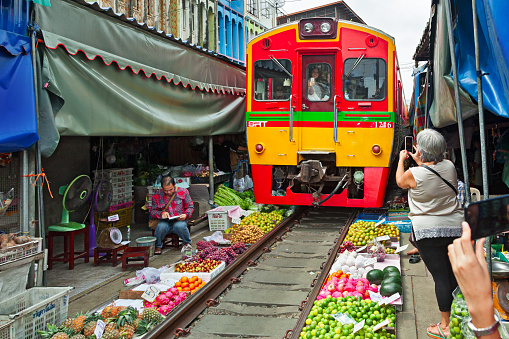 Arrival of the train in the Maeklong Railway Market, a local market commonly called Siang Tai (life-risking) Market. Spreading over a 100-metre length, the market is located by the railway near Mae Klong Railway Station