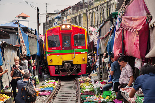 Arrival of the train in the Maeklong Railway Market, a local market commonly called Siang Tai (life-risking) Market. Spreading over a 100-metre length, the market is located by the railway near Mae Klong Railway Station