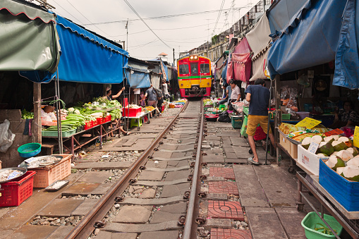 Arrival of the train in the Maeklong Railway Market, a local market commonly called Siang Tai (life-risking) Market. Spreading over a 100-metre length, the market is located by the railway near Mae Klong Railway Station