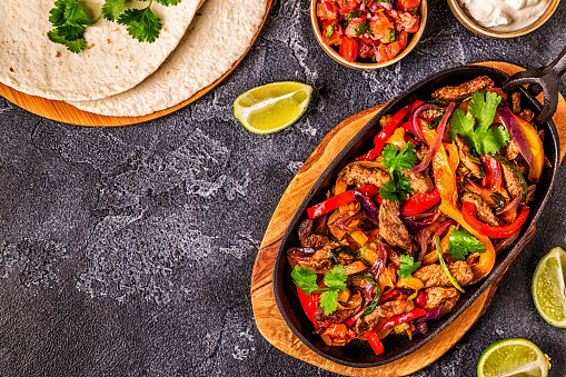 FAJITAS with colored pepper and onions, served with tortillas, salsa and sour cream.