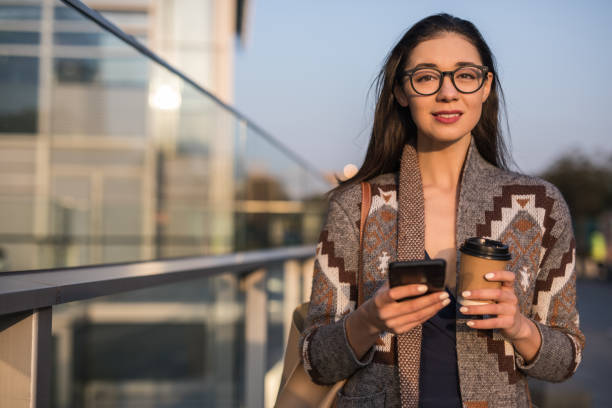 istock Pretty woman with takeaway coffee is text messaging 1134752304