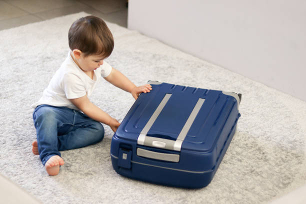 istock Cute little baby boy closing blue suitcase finished packing for vacation. Getting ready for traveling with child. Opening baggage at hotel room. 1134753688