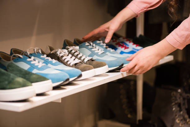 istock Woman puts sneakers collection on store rack. 1134757666