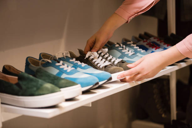 Hands put sneakers collection on store rack. Woman puts sneakers suede shoes collection on store rack. Female consultant arrange colorful new shoes for sale at boutique mall. womens blue suede shoes stock pictures, royalty-free photos & images