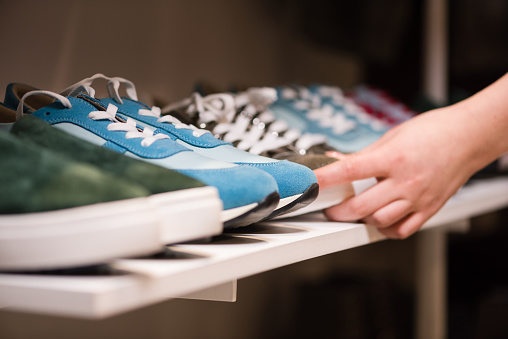 Manos femeninas ponen colección de zapatillas en el estante de la tienda photo