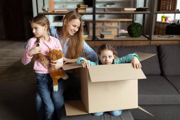 istock Young mom playing with kids daughers, laughing unpacking 1134758399