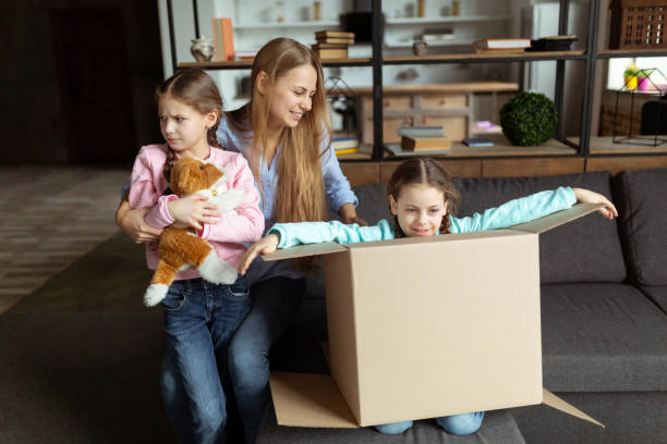 istock Young mom playing with kids daughers, laughing unpacking 1134758401