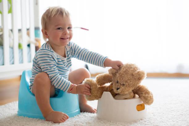 Cute toddler boy, potty training, playing with his teddy bear Cute toddler boy, potty training, playing with his teddy bear on potty potty toilet child bathroom stock pictures, royalty-free photos & images