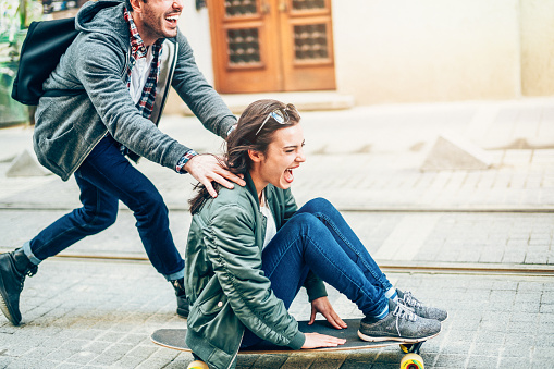 Portrait of happy couple riding skateboards and having fun outdoors. People teenager happiness concept