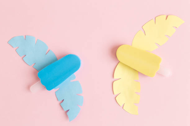 Ice cream and tropical leaves against pastel pink background abstract.