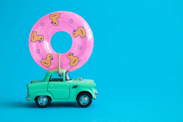 Car toy and inflatable pool float against blue background on the road abstract.