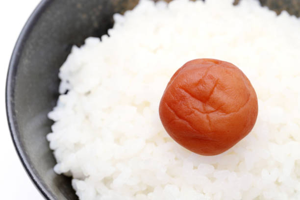 Japanese cooked white rice with Umeboshi on a bowl, on white background