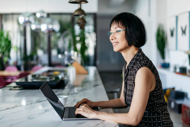 Efficient Chinese businesswoman using laptop and smiling