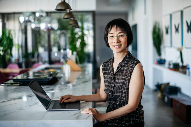 istock Attractive Chinese woman in her 60s using laptop and smiling 1134789840
