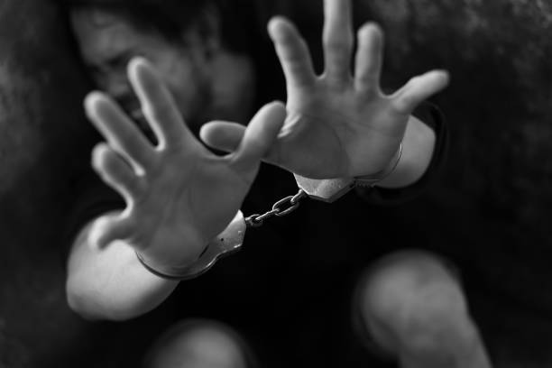 istock Man prisoner with his hands shackled in chains on a dark background. 1134801669