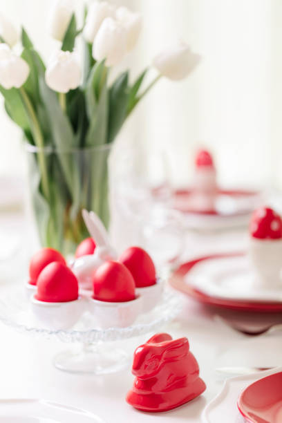 istock Happy easter. Decor and table setting of the Easter table is a vase with white tulips and dishes of red and white color. Easter colored eggs with white polka dots. 1134807324
