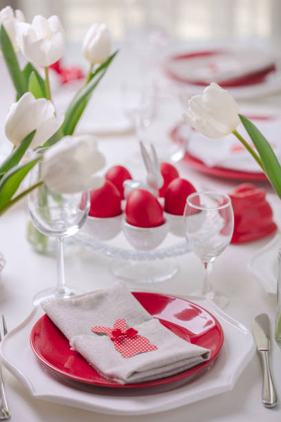 istock Happy easter. Decor and table setting of the Easter table is a vase with white tulips and dishes of red and white color. Easter colored eggs with white polka dots. 1134807328