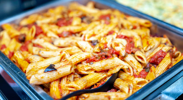 Freshly cooked Italian penne pasta in bolognese sauce Freshly cooked Italian penne pasta in bolognese sauce in a warming tray as a catering concept. tray photos stock pictures, royalty-free photos & images