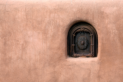 Old adobe wall security window in Santa Fe New Mexico.