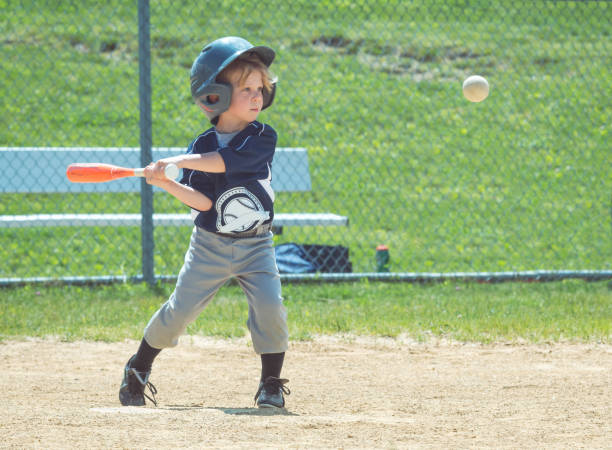 um jogador de basebol novo toma um balanço na esfera - boys playing baseball - fotografias e filmes do acervo