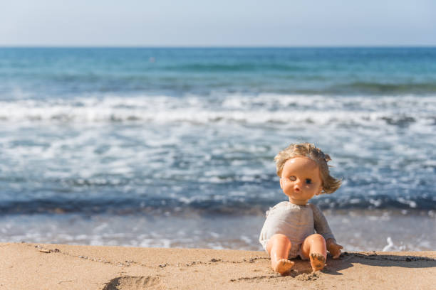 istock Old Broken Toy Doll Sitting on a Beach in Italy 1134813995