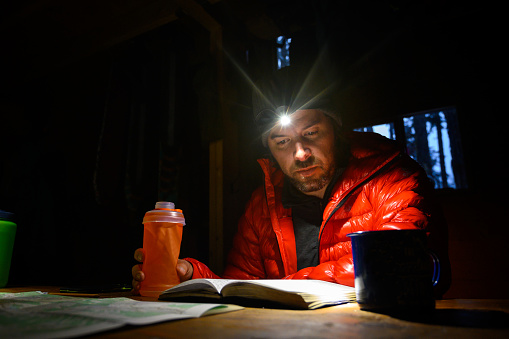 Man reading an adventure journal by headlamp