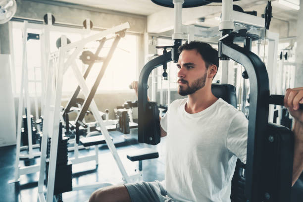 hübsches man ist das training mit pectoral machine in fitness club., portrait of strong man doing out calories burning in gym., gesundes und fitness-lifestyle-konzept. - brustmuskeln stock-fotos und bilder