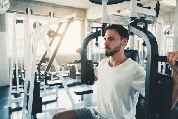 handsome man is exercising with pectoral machine in fitness club.,portrait of strong man doing working out calories burning in gym., healthy and fitness lifestyle concept. - pectoral muscle imagens e fotografias de stock