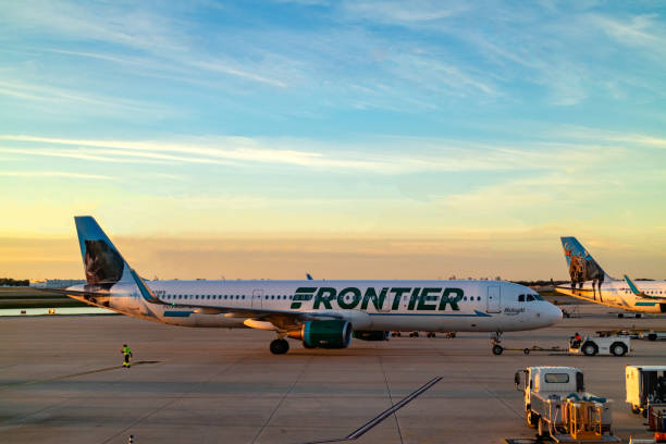Orlando, Florida, USA - A Frontier Airlines Airplane Is Being Pushed Back To Taxi For Take-Off At Orlando International Airport At Almost Sunset Time Orlando, USA - January 25, 2019: A Frontier Airlines Jet airplane is being pushed back to enable the pilot to taxi to his take-off point on the runway for departure at Orlando International Airport in Florida in the USA. There is a wolf painted on the tailplane. In the foreground are airport operational equipment. It is almost sunset time. Copy space. its almost time stock pictures, royalty-free photos & images
