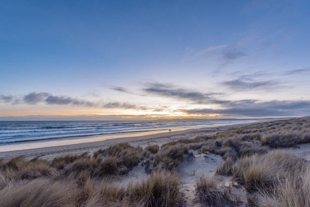 istock Couple in distance walking along beach at sunset. 1134816329