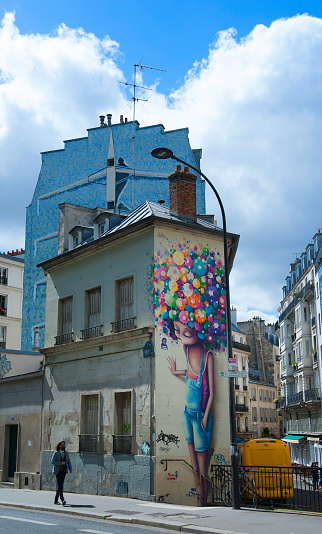 Paris-France, April 25, 2018; Young man walking in front of colorful graffiti in Paris
