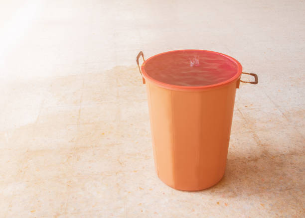 water leak drop interior office building in red bucket from Ceiling and flow on terrazzo floor