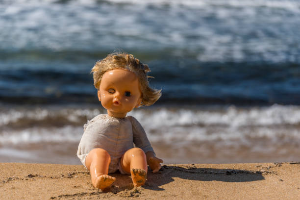 istock Old Broken Toy Doll Sitting on a Beach in Italy 1134826192