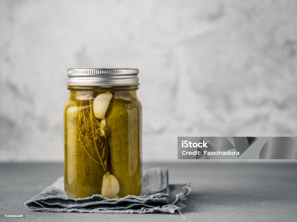 Glass jar with pickled cucumbers, copy space Glass jar with pickled cucumbers on gray background with copy space for text. Perfect homemade marinated cucumbers in mason jar on rustic table. Pickle Stock Photo