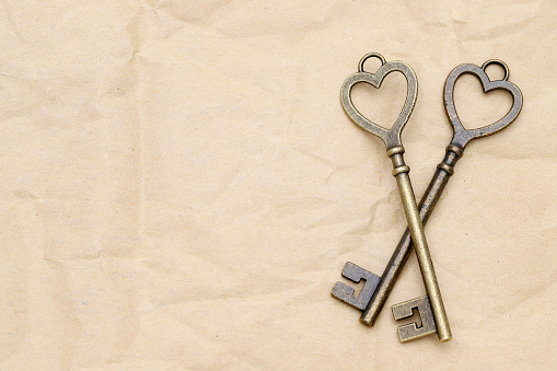 heart shaped vintage golden key on brown paper background