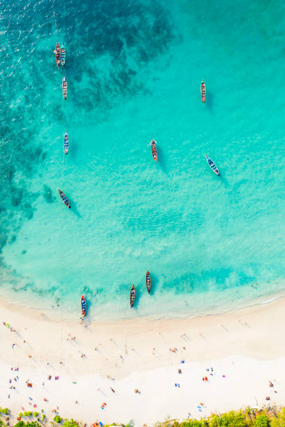 blick von oben, atemberaubender blick aus der luft auf einen wunderschönen tropischen strand mit weißem sand und türkisfarbenem wasser, langschwanzbooten und liegewiesen, banana-strand, phuket, thailand. - strand patong stock-fotos und bilder