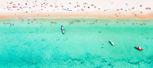 白い砂浜とターコイズブルーの澄んだ水、ロングテールボート、日光浴をしている人、スリンビーチ、プーケット、タイなどの美しいトロピカルビーチの素晴らしい空からの眺め。 - サトゥーン県 ストックフォトと画像