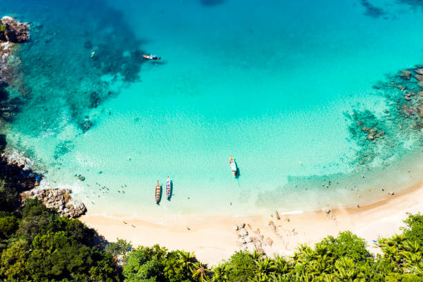 白い砂浜とターコイズブルーの澄んだ水、ロングテールボート、日光浴をしている人、バナナビーチ、プーケット、タイなどの美しいトロピカルビーチの素晴らしい空からの眺め。 - サトゥーン県 ストックフォトと画像