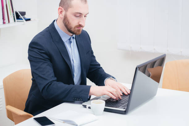 istock Elegant business man in a suit sitting in the office and using  laptop computer . 1134838267