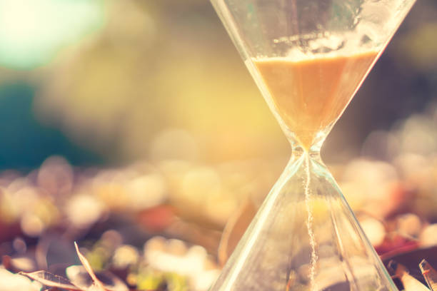 istock Small hourglass show time is flowing on old wood grunge texture background. 1134839973