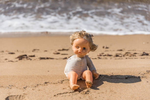 istock Old Broken Toy Doll Sitting on a Beach in Italy 1134840186