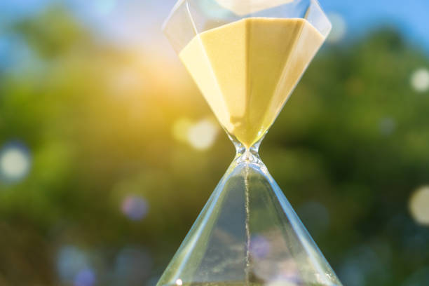 istock Small hourglass show time is flowing on old wood grunge texture background. 1134840902