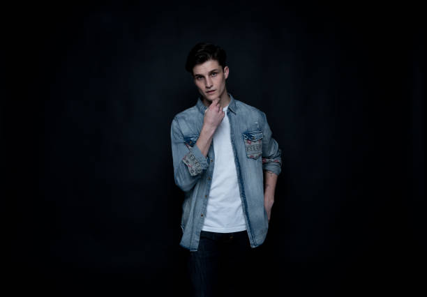 Good looking man wearing a button down shirt in front of black background