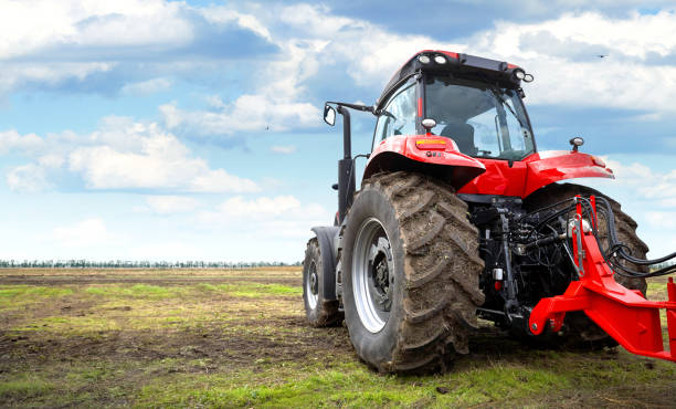 istock Tractor working in a field against a cloudy sky 1134848216
