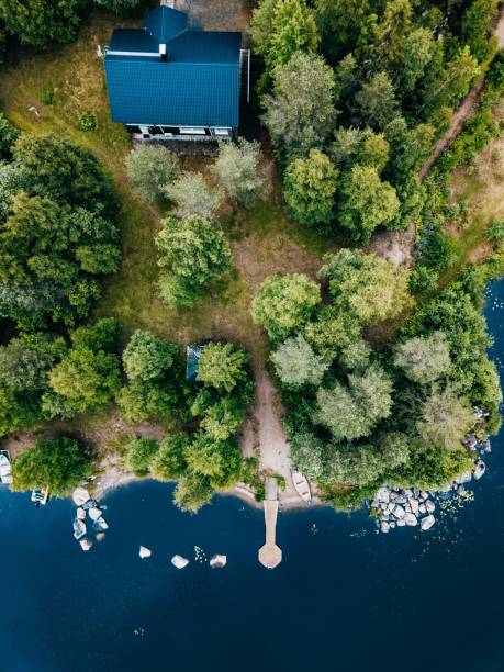 aerial view of wooden cottage in green forest by the blue lake in rural summer finland - finland sauna lake house imagens e fotografias de stock