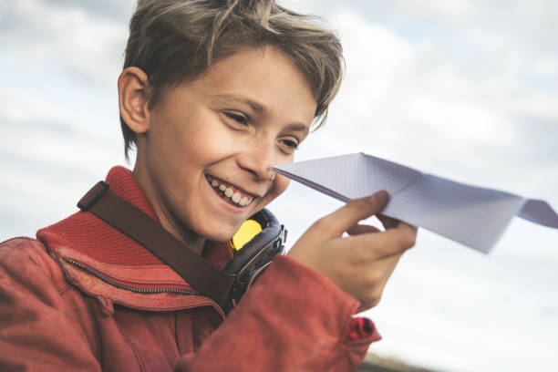 istock Smiling Boy Playing With Paper Airplane Against Cloudy Sky 1134850479