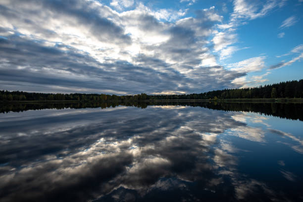 istock calm lake in bright sun light with reflections of clouds and trees and blue sky 1134851155