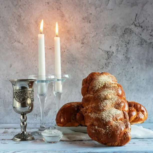 Shabbat Shalom - challah bread, shabbat wine and candles on wooden table.