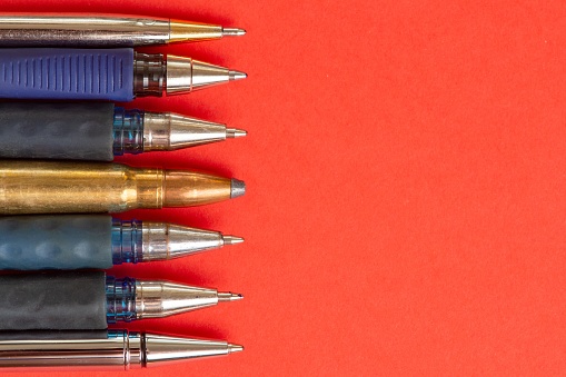 Bullet and pens on red background. Freedom of the press is at risk concept. World press freedom day concept.